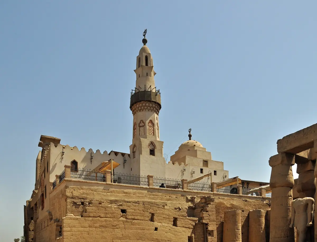 Minaret of the mosque rising above the stone walls of Luxor Temple