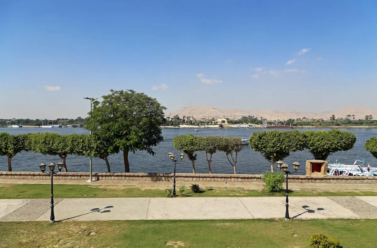 Nile riverbank with trees and a paved walkway on the Luxor Corniche
