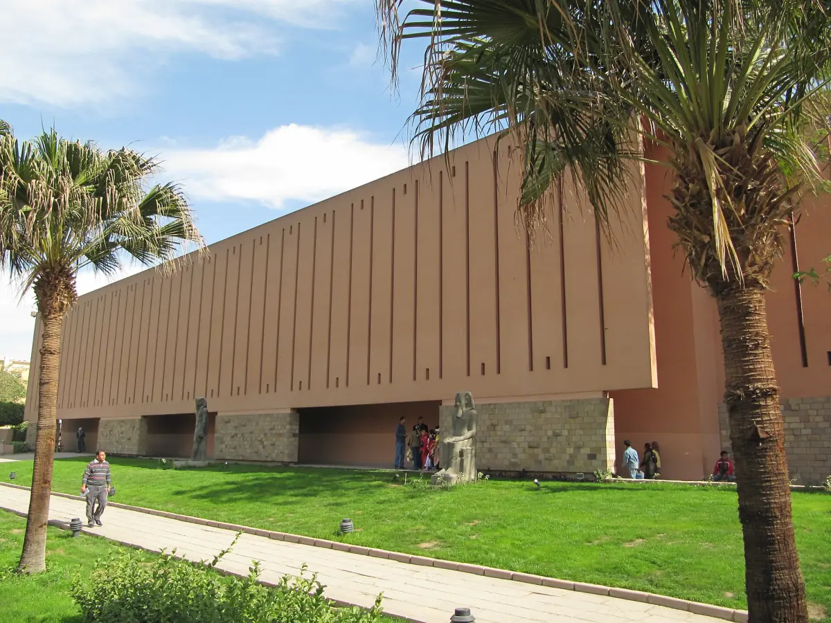Modern sandstone-coloured building of the Luxor Museum with palm trees and lawn