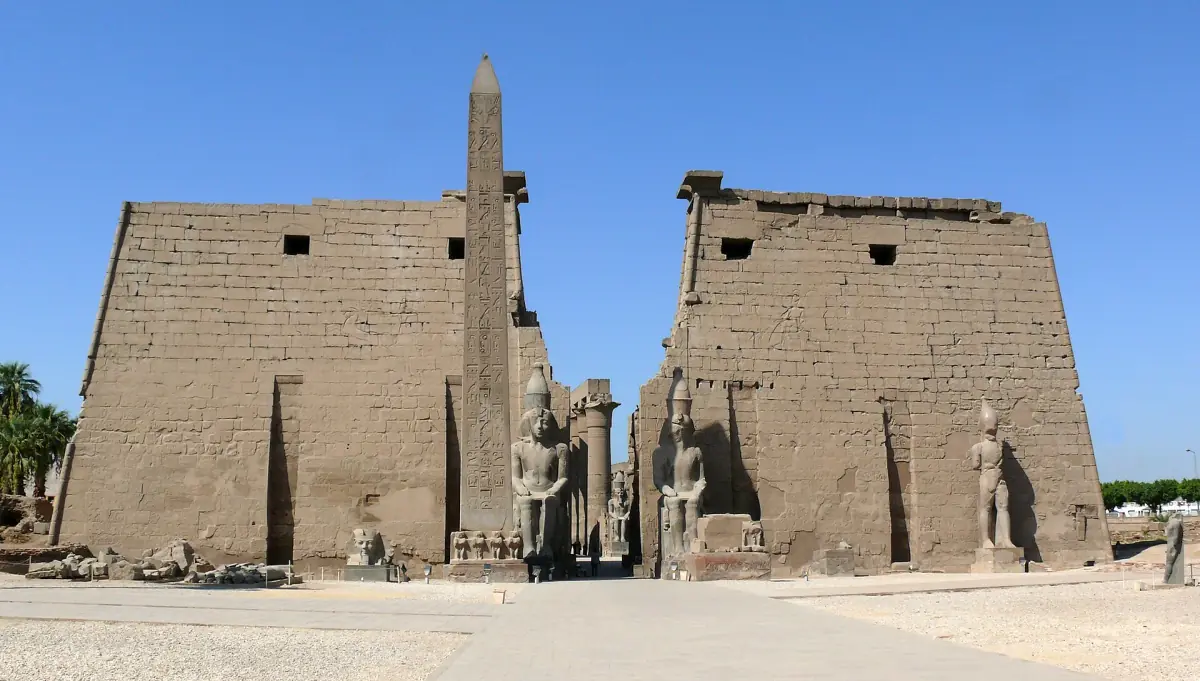 Entrance pylon of Luxor Temple with obelisk and colossal statues under a clear blue sky