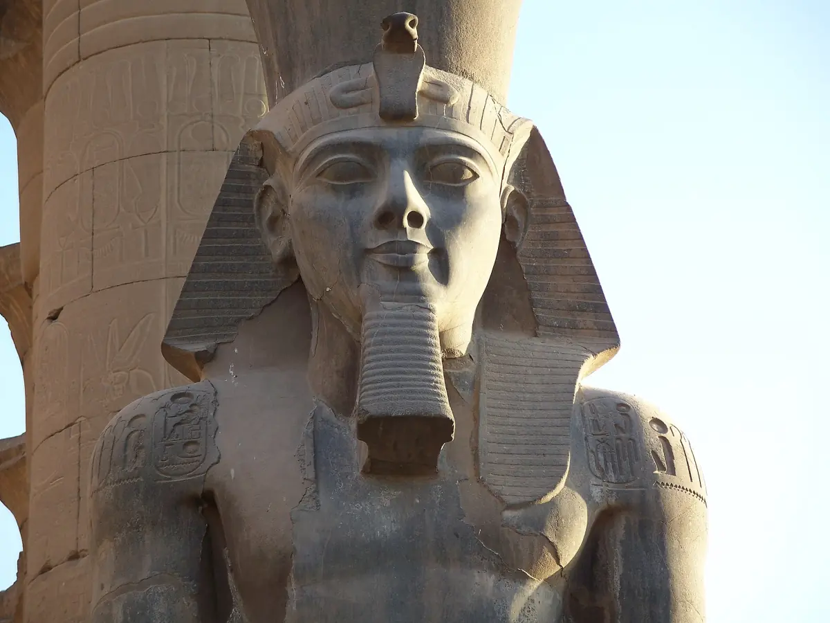 Close view of a colossal pharaoh statue with crown and beard at Luxor Temple