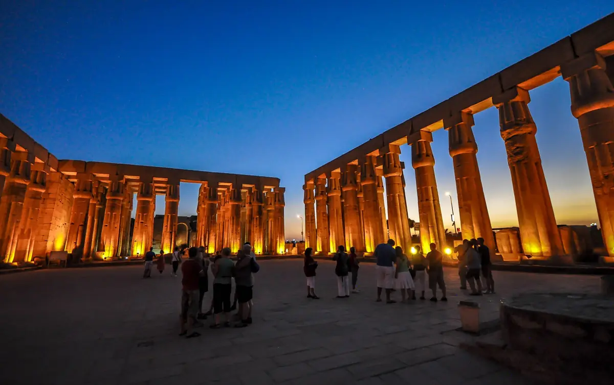 Columned court of Luxor Temple at dusk with the first floodlights switched on